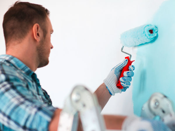 stock-photo-repair-building-and-home-concept-close-up-of-male-in-gloves-holding-painting-roller-184931876